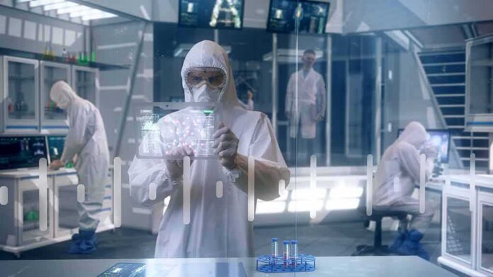 shutterstock_1686897298 Scientist in hazmat suit using a transparent digital tablet in a lab