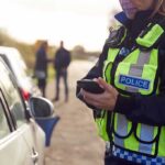 Police officer using a smartphone during a roadside stop