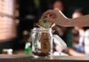 Madison Grab? Tips, OT Still Taxed Hand placing cash into a tip jar on a counter