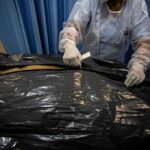 Healthcare worker sealing a body bag