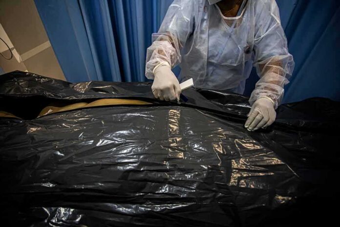 Healthcare worker sealing a body bag