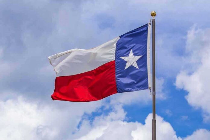 shutterstock_2005683734 Texas state flag waving on a pole against a cloudy sky