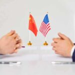 Xi’s Blunt Taiwan Warning Shocks Trump Two diplomats sit across table with China and United States flags between them
