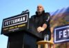 Democrats On Notice: Fetterman Draws Blood-Red Line Speaker at outdoor rally standing at podium with microphone