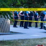 Custody Death Ignites Bologna Chaos police officers stand behind caution tape at a park scene