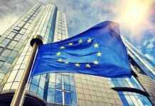 Massive EU Overhaul – Brussels Power Grab Looms European Union flag waving in front of modern glass office buildings