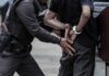 Police officer handcuffing a person against a vehicle