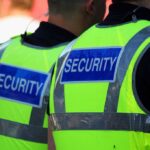Two security personnel wearing high visibility vests with SECURITY printed on the back
