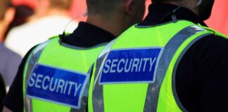 Two security personnel wearing high visibility vests with SECURITY printed on the back