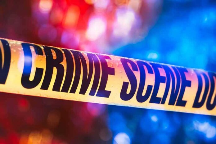 shutterstock_1019899543-2 Crime scene tape with blurred emergency lights in background