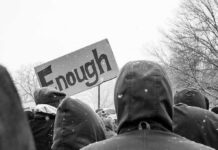 Organized Violence? Europe Burns; Washington Drops Terror Hammer crowd in winter coats at a protest holding a sign