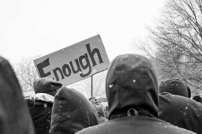 crowd in winter coats at a protest holding a sign