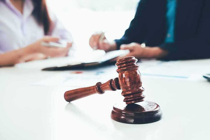shutterstock_1070756789 judge's gavel on table with people discussing documents in background