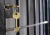 Golden key hanging from a lock on a metal jail cell door
