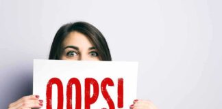 Woman holding a sign that says OOPS in red