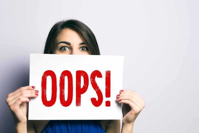 Woman holding a sign that says OOPS in red