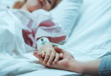 Autonomy Or State-Approved Exit? Patient in hospital bed with IV line holding a visitor's hand