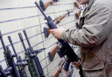 Teens Arm Cartels – High School Gun Pipeline Exposed Person examining a black rifle in a gun store