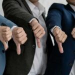 Businesspeople giving thumbs down in a row