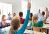 Judge Smacks Down Campus Gag Order Students raise hands in a classroom with a teacher at the front