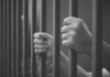 Illinois Blowback: Detainers Dodged, Danger Rises hands gripping prison bars