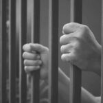 hands gripping prison bars
