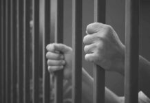 Illinois Blowback: Detainers Dodged, Danger Rises hands gripping prison bars