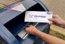 DOJ Slams Brakes – Noncitizen List Sparks Furious Court Fight Person mailing a ballot into a blue street mailbox