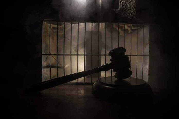 Judge’s gavel in silhouette before prison bars