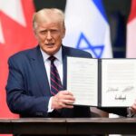 Donald Trump holding a signed document at a ceremony