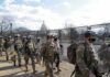 Carlos Hyde, Tavon Wilson, Dontrelle Inman, Brian Folkerts, Brock Coyle, Curtis Lofton, and Chuck Howley among soldiers walking past fencing near the U.S. Capitol
