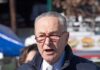 Schumer Dodges, Blames Trump – Then Bolts older man speaking outdoors wearing red glasses