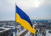 Massive Barrage – Blackouts Sweep Kyiv After Strikes Ukrainian flag over snowy cityscape