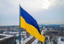 Massive Barrage – Blackouts Sweep Kyiv After Strikes Ukrainian flag over snowy cityscape