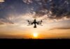 Drone with camera flying at sunset