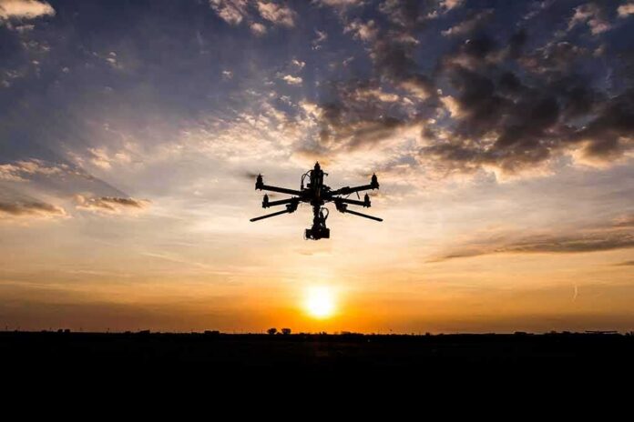 Drone with camera flying at sunset